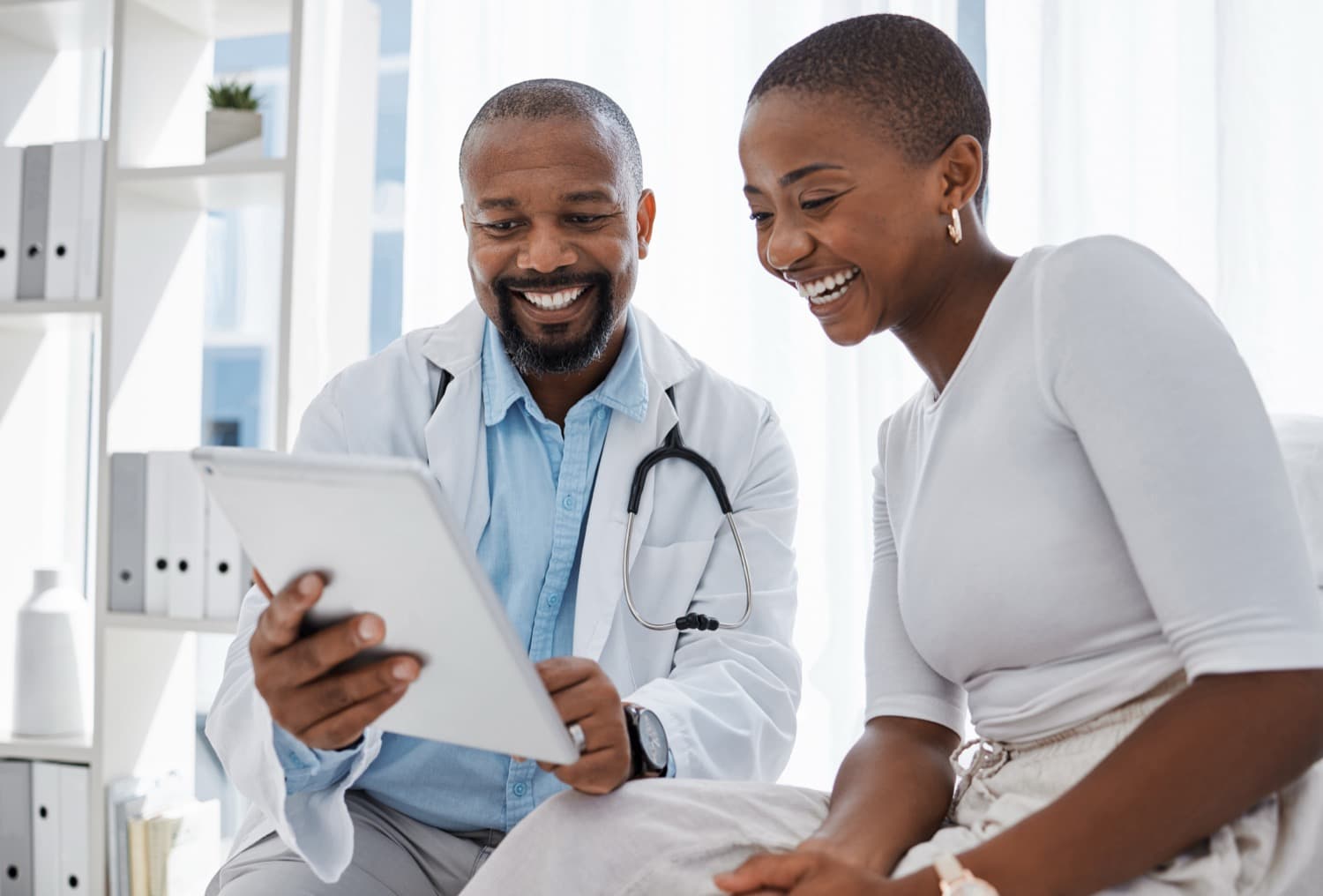 A doctor and a smiling patient looking at a tablet together
